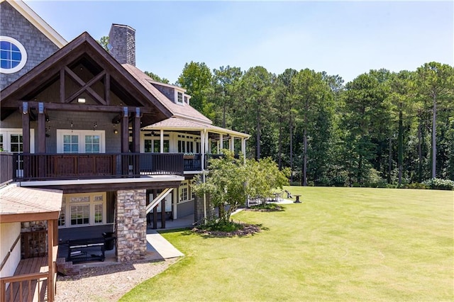 back of house featuring a patio area, a deck, a lawn, and a chimney