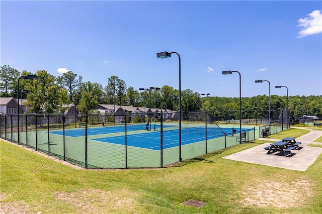 view of tennis court featuring a yard and fence