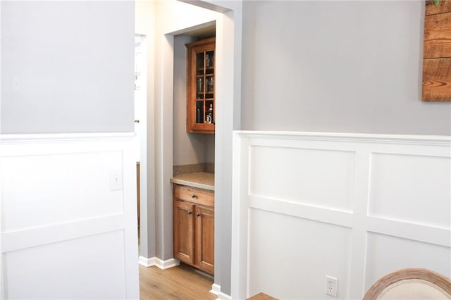 hallway featuring light wood-style flooring and wainscoting