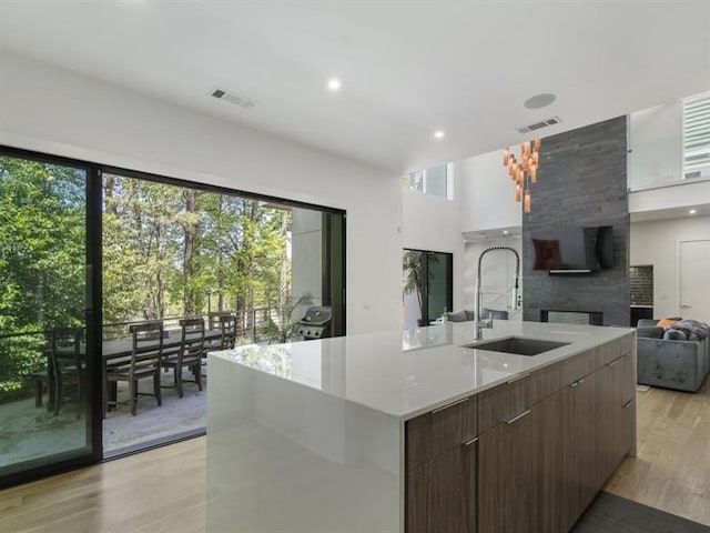 kitchen with sink, light hardwood / wood-style floors, a healthy amount of sunlight, and a spacious island