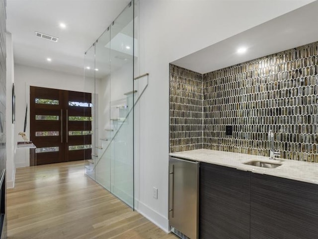 bathroom with a shower with door, vanity, hardwood / wood-style floors, and backsplash