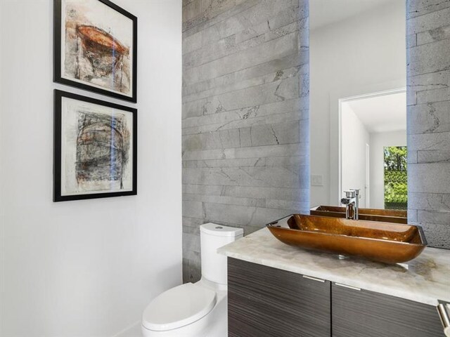 bathroom with tile walls, vanity, and toilet