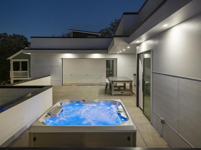 patio at twilight featuring an outdoor hot tub