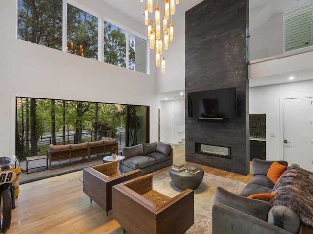 living room with a high ceiling, a fireplace, light wood-type flooring, and a chandelier