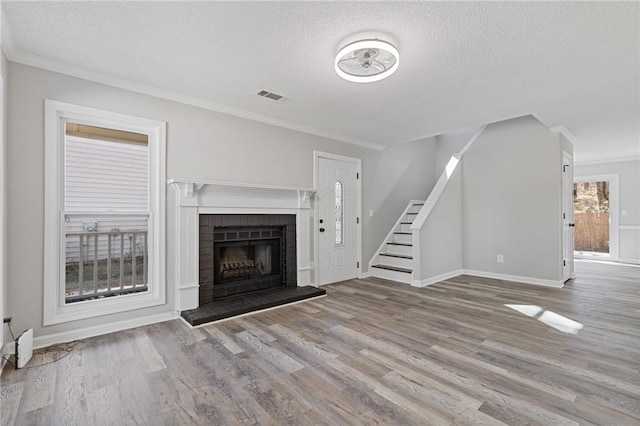 unfurnished living room featuring visible vents, crown molding, stairway, and wood finished floors