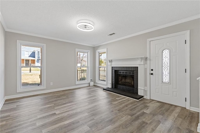 unfurnished living room featuring plenty of natural light, a fireplace, visible vents, and wood finished floors