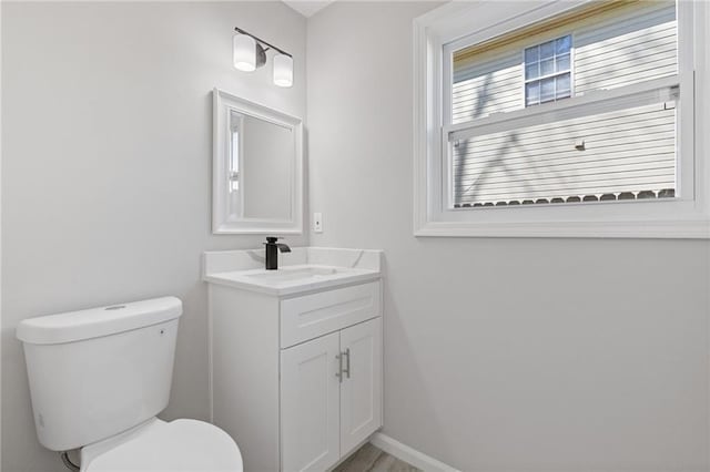 bathroom featuring baseboards, vanity, and toilet