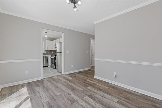 interior space with ornamental molding, light wood-style flooring, and baseboards