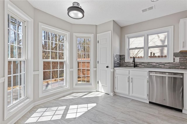 kitchen with a wealth of natural light, stainless steel dishwasher, a sink, and visible vents