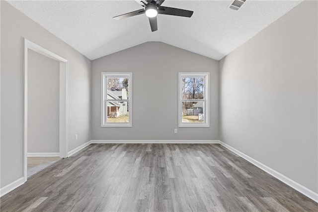 spare room with a wealth of natural light, visible vents, a textured ceiling, and wood finished floors