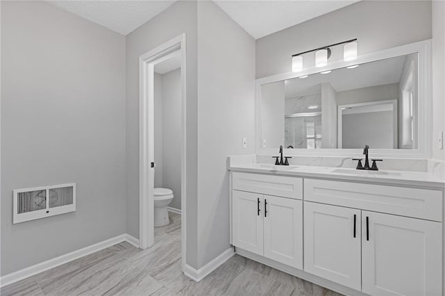 full bathroom with toilet, a sink, visible vents, and a shower stall