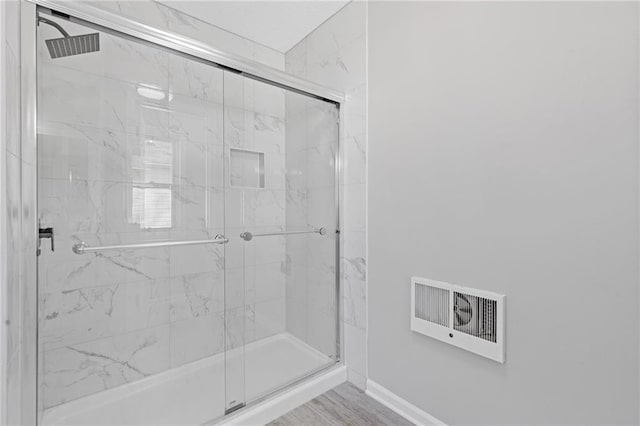 bathroom with a stall shower, baseboards, and wood finished floors