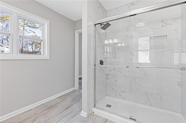 full bathroom with a marble finish shower and baseboards