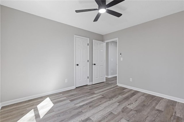 spare room featuring a ceiling fan, baseboards, and wood finished floors