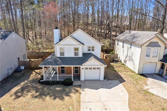 view of front of home with concrete driveway, a chimney, an attached garage, covered porch, and fence