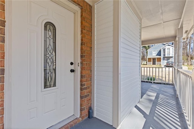 view of exterior entry featuring a porch and brick siding