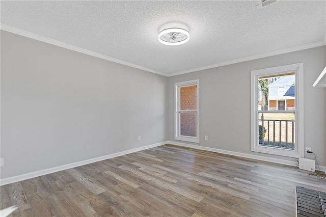 spare room featuring crown molding, a textured ceiling, baseboards, and wood finished floors