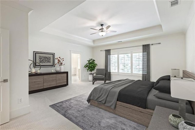 carpeted bedroom with a raised ceiling and ceiling fan