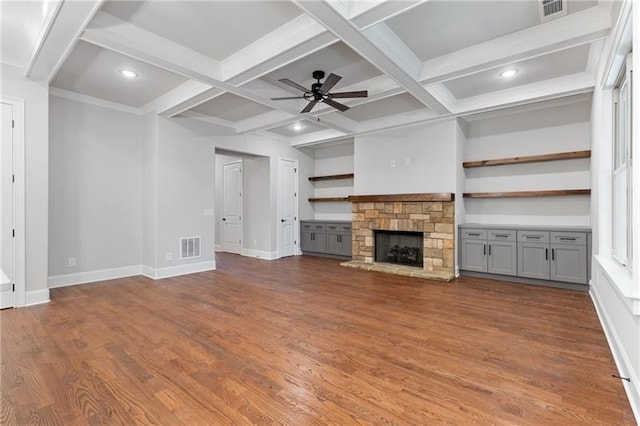 unfurnished living room featuring coffered ceiling, a stone fireplace, dark hardwood / wood-style floors, and beam ceiling