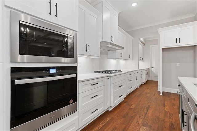 kitchen featuring white cabinetry, ornamental molding, dark wood-type flooring, and stainless steel appliances