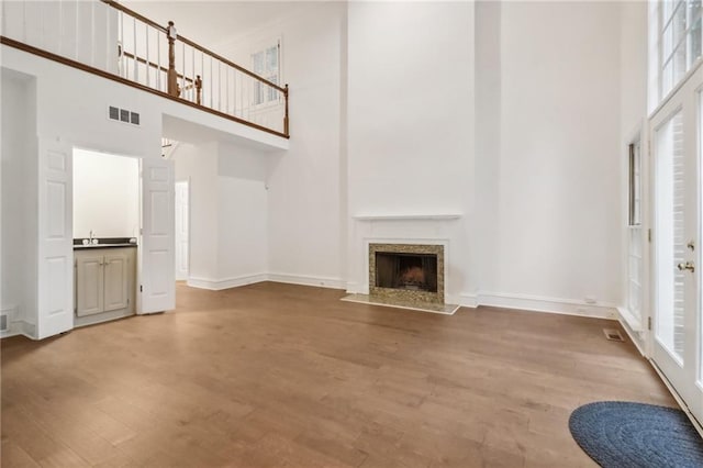 unfurnished living room with sink, a fireplace, hardwood / wood-style floors, and a high ceiling