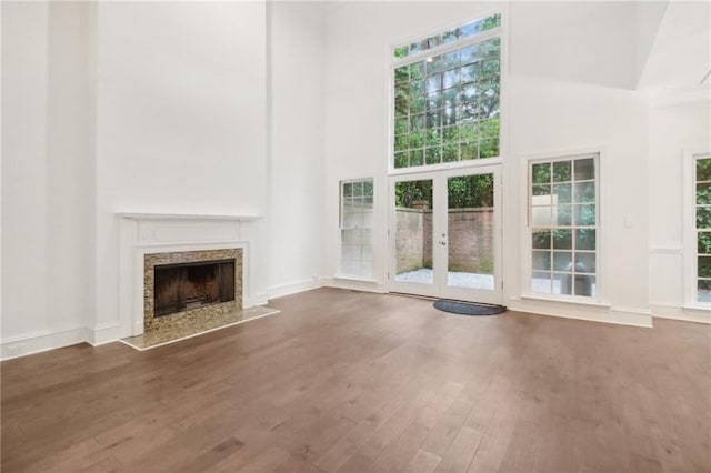 unfurnished living room with a premium fireplace, french doors, dark hardwood / wood-style floors, and a high ceiling