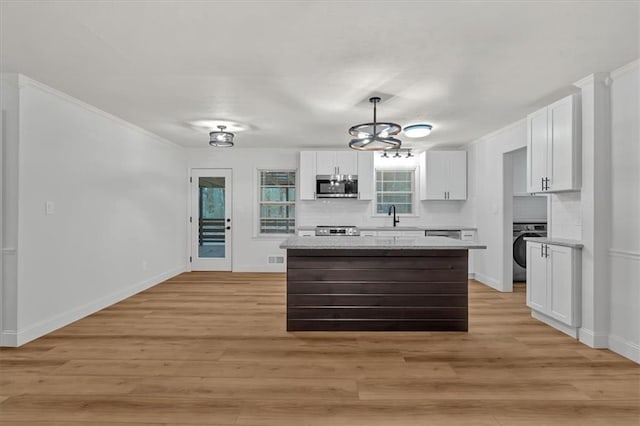 kitchen featuring pendant lighting, washer / dryer, a kitchen island, and white cabinets