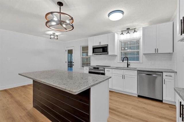 kitchen with white cabinetry, appliances with stainless steel finishes, a kitchen island, and hanging light fixtures