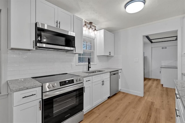 kitchen with white cabinetry, sink, backsplash, stainless steel appliances, and light stone countertops