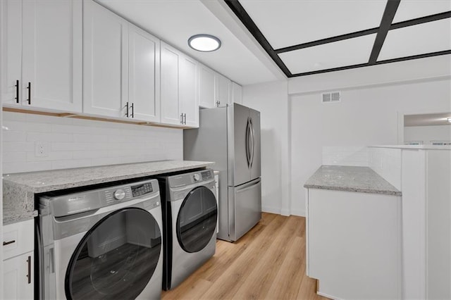 clothes washing area with independent washer and dryer and light hardwood / wood-style floors