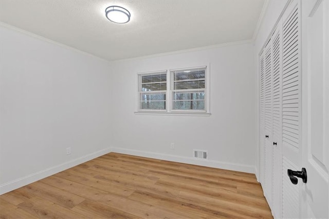 unfurnished bedroom featuring ornamental molding, a closet, and light wood-type flooring