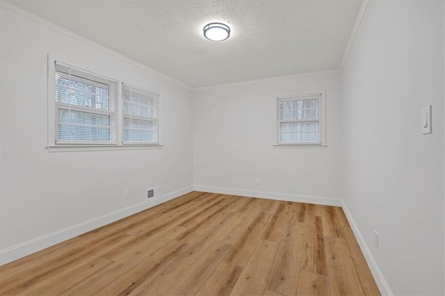 empty room featuring crown molding, a textured ceiling, and light wood-type flooring