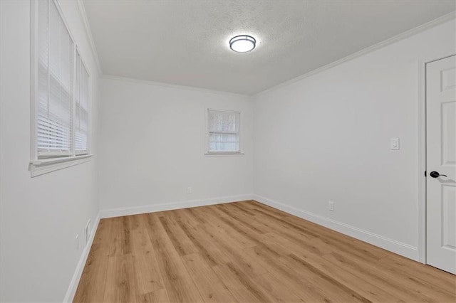 spare room featuring ornamental molding, light hardwood / wood-style flooring, and a textured ceiling