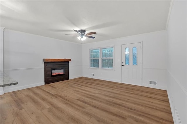 unfurnished living room with ornamental molding, ceiling fan, and light wood-type flooring