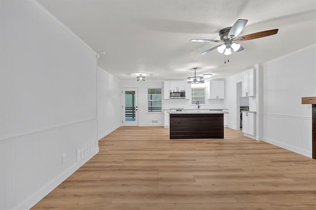 kitchen with crown molding, ceiling fan with notable chandelier, white cabinets, and light wood-type flooring