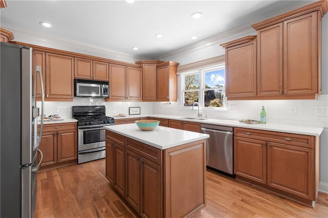 kitchen with a sink, crown molding, stainless steel appliances, and wood finished floors