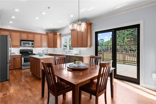 dining space with crown molding, an inviting chandelier, recessed lighting, and light wood-style flooring