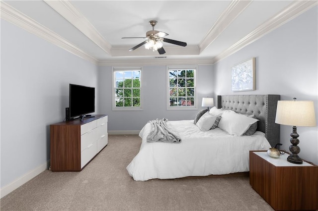 bedroom featuring baseboards, ornamental molding, a tray ceiling, and light carpet