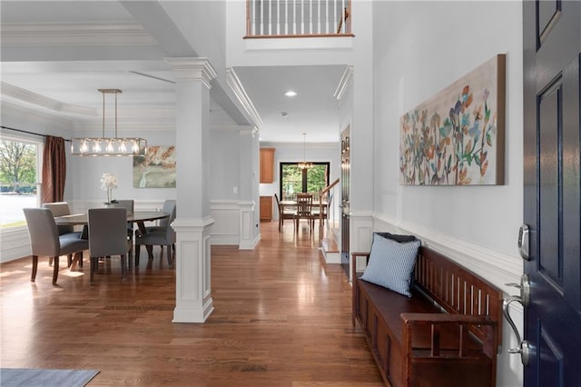 entrance foyer with an inviting chandelier, decorative columns, crown molding, and wood finished floors