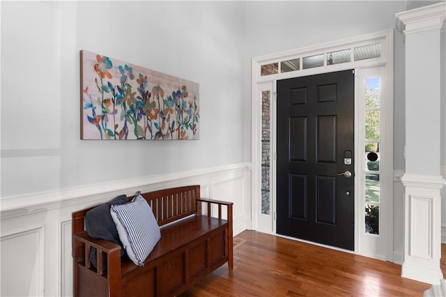 entrance foyer with wainscoting, a decorative wall, decorative columns, and wood finished floors