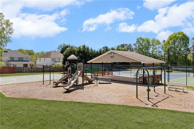communal playground featuring a lawn and fence