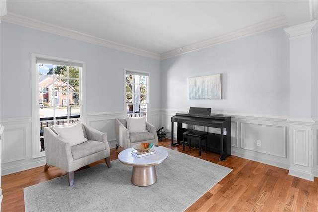 living area featuring light wood-style floors, ornamental molding, wainscoting, and a wealth of natural light