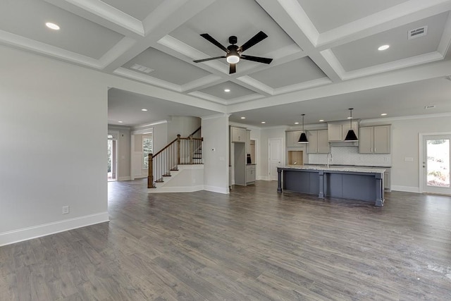 unfurnished living room featuring beamed ceiling, stairway, coffered ceiling, and visible vents