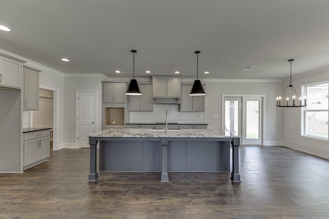 kitchen with a kitchen island with sink, pendant lighting, and gray cabinetry