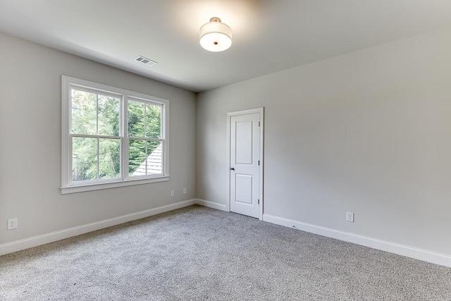 carpeted spare room featuring visible vents and baseboards