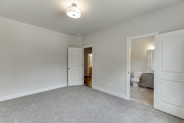 unfurnished bedroom featuring baseboards, connected bathroom, and light colored carpet