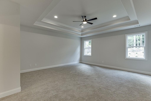 spare room with a tray ceiling, recessed lighting, visible vents, light carpet, and baseboards