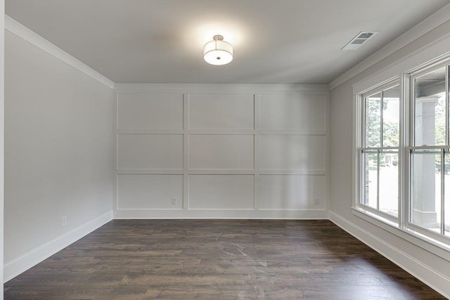 empty room featuring visible vents, a decorative wall, and dark wood-type flooring