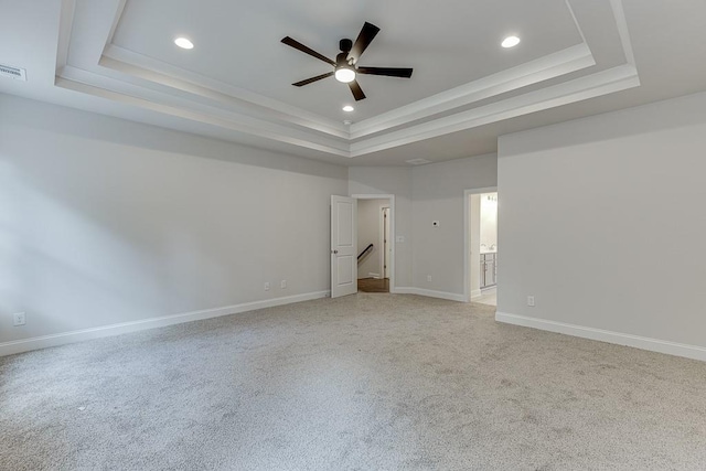 empty room featuring baseboards, a raised ceiling, a ceiling fan, and light colored carpet