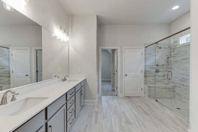 full bath featuring baseboards, double vanity, a sink, and a shower stall